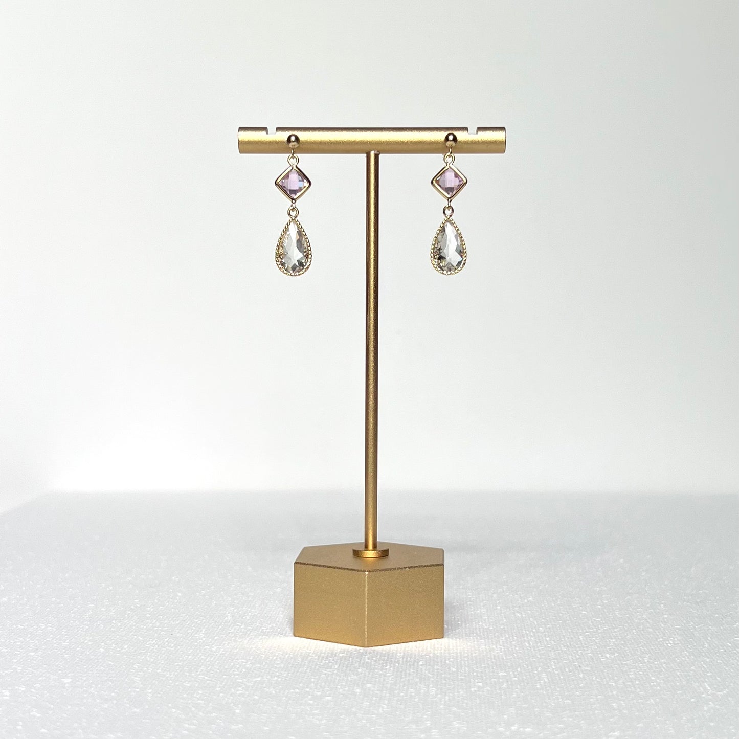 This earring set features a petite pink glass bezel set charm with a clear crystal teardrop shape fancy prong bezel setting hung on a 3mm gold filled earring stud post.