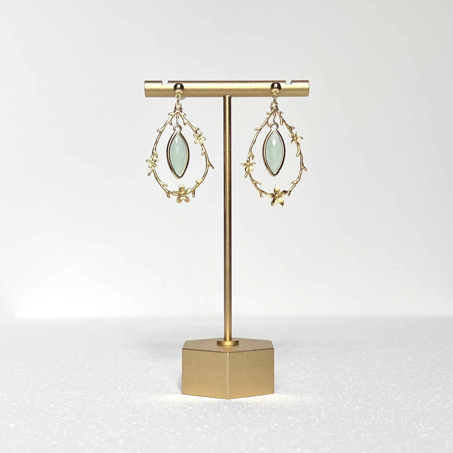 This earring set features a gold branch & flower hoop in which hangs a minty green glass marquise shaped bezel set charm, hung on a gold filled 4mm ball stud earring post. 